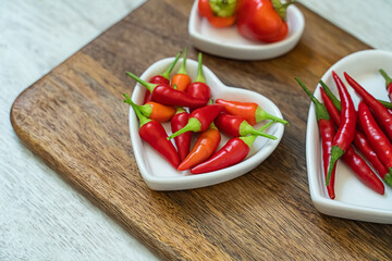 assorted red chili peppers and heart shaped plate set selective focus