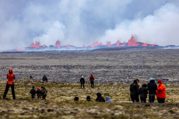 Tourists looking at and walking towards volcanic eruption on the Reykjanes peninsula in Iceland