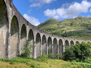 Obraz premium Glenfinnan Viaduct with Scottish Highlands mountains in the background, Scotland, United Kingdom, August 2022