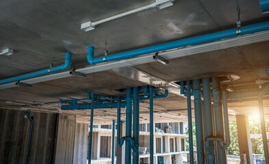 A large building currently under construction that has many blue pipes