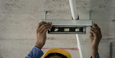 A man in a hard hat is working with level tool