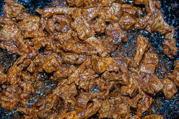 asia fried meat slices close-up on a background of a frying pan base for paprikash
