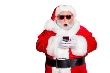 Portrait of impressed christmas father in hat using cell phone  device screaming omg wearing read about festive events eyeglasses eyewear belt isolated over red background