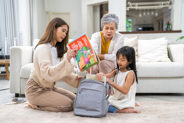 Asian family preparing school backpack together, mother, grandmother and girl child organizing books, back to school concept, family bonding time, education and learning preparation, supportive family