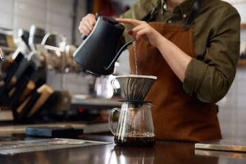 Cropped shot of barista hands pouring boiling water into filter coffee pot