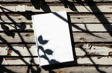 Blank Book on Rustic Wooden Surface with Branch Shadows