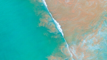 Aerial view of turquoise ocean wave reaching the coastline. Beautiful tropical beach from top view. summer background.