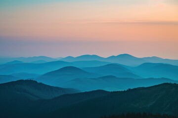Obraz premium Layers of blue mountain ridges at sunrise. Serene landscape with pastel sky.