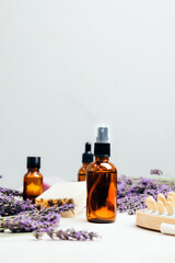 Set of natural cosmetics. Amber bottles with facial, bath liquid on a concrete background with lavender flowers. Front view