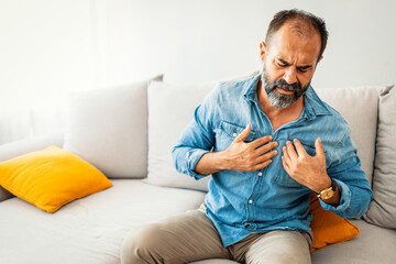 Middle-Aged Man Experiencing Chest Pain on Sofa