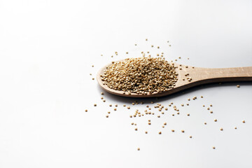 quinoa in the wooden spoon with seeds on white surface. Copy space
