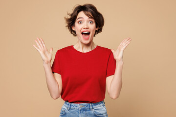 Young shocked surprised happy woman she wearing red t-shirt casual clothes look camera spreading...