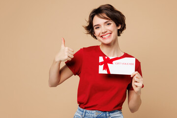 Young happy woman wear red t-shirt casual clothes hold gift certificate coupon voucher card for...