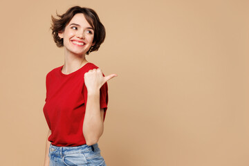 Side view young happy woman she wear red t-shirt casual clothes point thumb finger aside on empty...