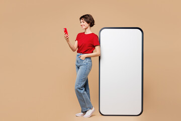 Full body side view young woman wear red t-shirt casual clothes big huge blank screen mobile cell...
