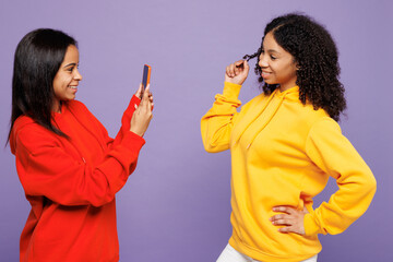 Two young happy little kid teen girls women they wear red yellow hoodie casual clothes taking photo...