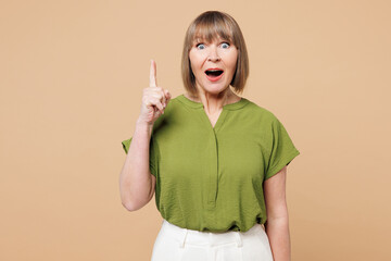 Elderly blonde woman 50s years old she wear green shirt casual clothes holding index finger up with...