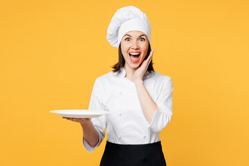 Young shocked chef cook baker woman she wear white shirt black apron uniform toque chefs hat hold...