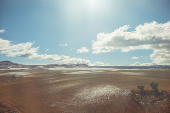 Snow patches on a vast rural landscape under a cloudy sky