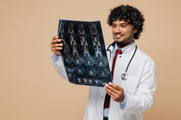 Young Indian doctor man wear white medical gown suit work in hospital clinic hold x-ray...