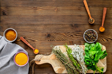 Colorful spices in wooden bowls and green herbs for cooking, top view