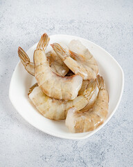 raw shrimps on the white plate, top view