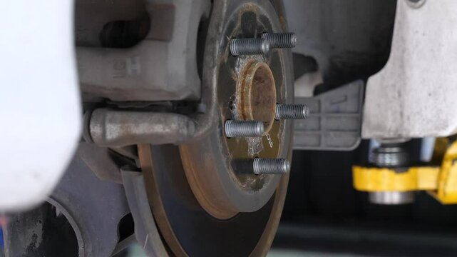 Close-up view of car wheel hub and brake disc assembly in auto repair shop, mechanical maintenance and repair.