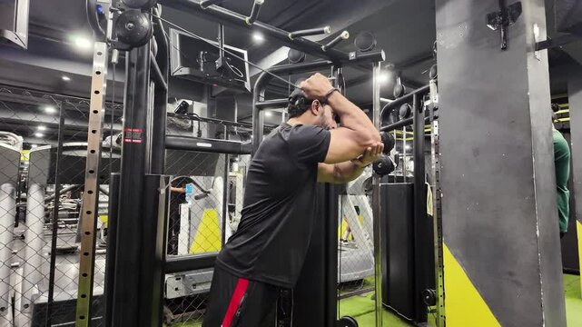 Young fit muscular man close up doing triceps pull down rope extension exercise in modern fitness center 