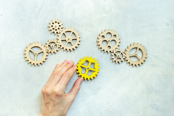 Hand is adding a cog wheel to a chain of gears. Idea or solution concept