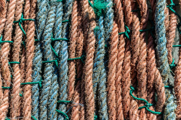 A close-up image of tightly woven, weathered ropes used in fishing nets. The detailed texture and rugged fibers show signs of wear, capturing the essence of maritime work.