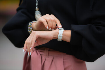 The woman looks at her wristwatch. Punctuality and the concept of time. Close-up of a woman's hand...