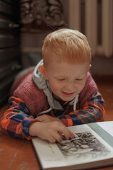 red haired child looking at photo album in old retro style apartment