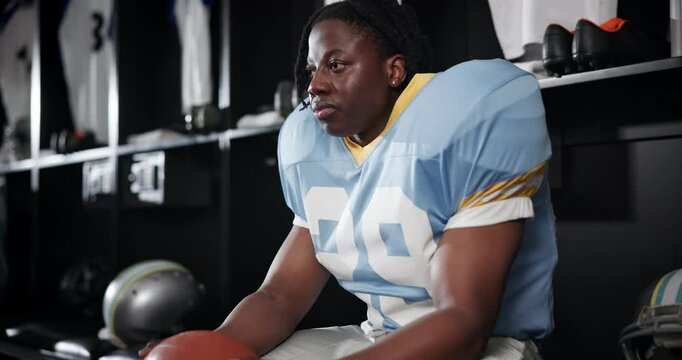 Football, game and black man with thinking in locker room for break, recovery and halftime anxiety. Athlete, worry and serious player with stress for sports tournament, mistake or match regret in USA