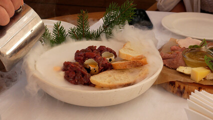 Venison tartare served with liquid nitrogen. Raw meat dish with quail egg. French delicacy, close-up shot
