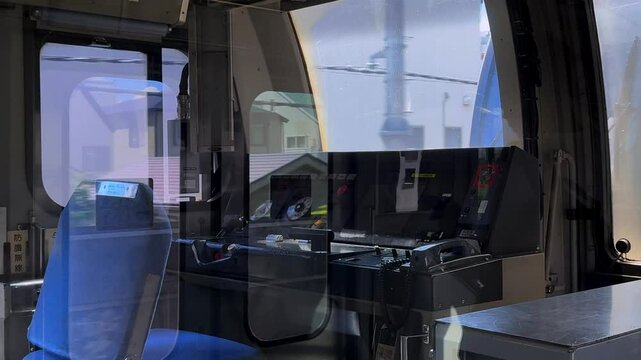 Empty train cockpit with control panels and blue seat, showing an inside view of a train in Tokyo