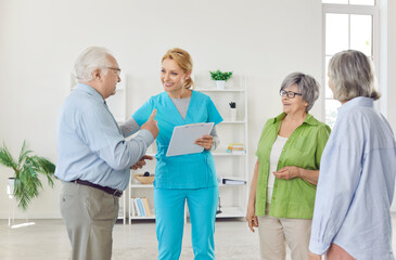 Fototapeta premium Doctor or nurse holding a meeting with a group of senior patients at a nursing home. The healthcare professional is talking and providing care, creating a happy and supportive environment.
