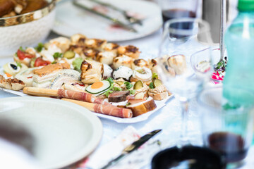 A beautifully arranged platter of assorted canapés and gourmet snacks set on a dining table for a festive gathering in late afternoon