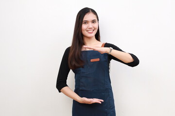 Young asian woman in blue apron showing something small on white studio background