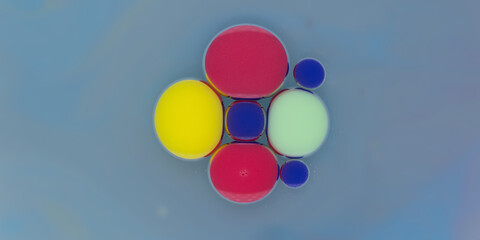 Colorful abstract arrangement of floating spheres in shades of red, yellow, blue, and green against a smooth, light blue background