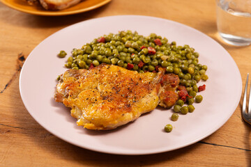 Fried boneless skinless chicken leg with green peas for garnish on plate
