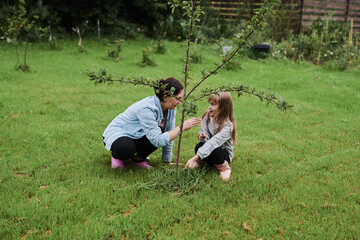 Little girl helping her mother work in the garden in the backyard of the house