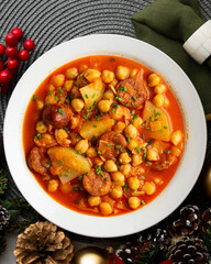 Delicious dish of braised chickpeas with spicy chorizo. Table with christmas decoration.