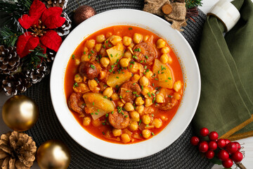 Delicious dish of braised chickpeas with spicy chorizo. Table with christmas decoration.