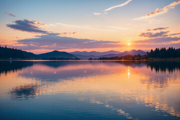 Fototapeta premium A beautiful sunset over a lake with mountains in the background