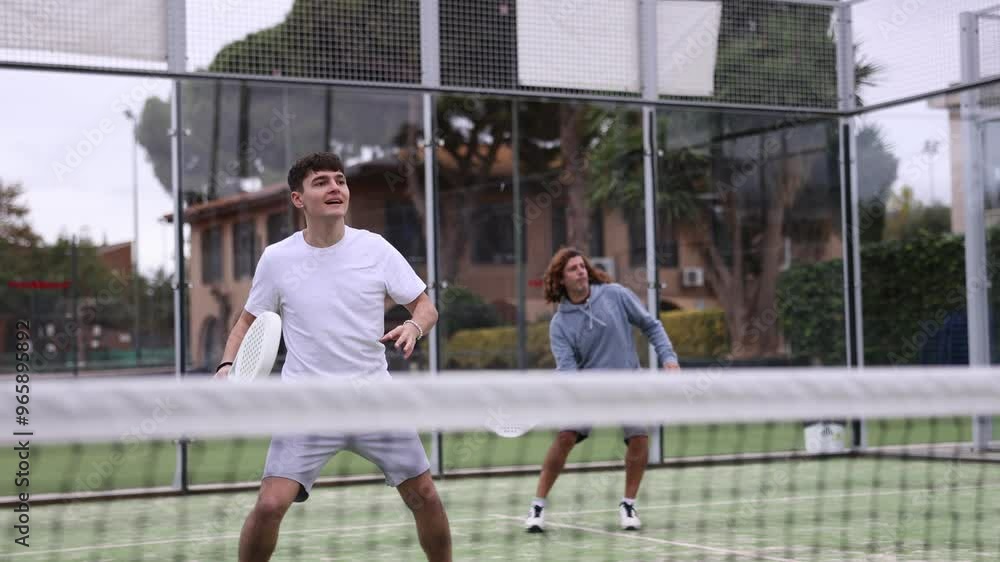 Canvas Prints Sportive men of different ages padel players hitting ball with racket on hard court in summer