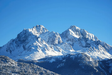 Snow covered mountains rise majestically against clear blue sky, showcasing beauty of nature. crisp air and serene landscape evoke sense of tranquility and wonder