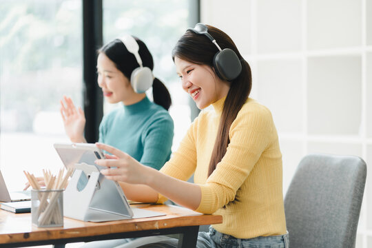Engaged women using tablets and headphones in modern workspace