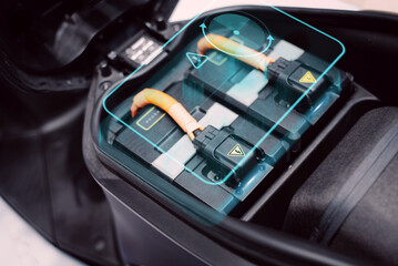 Close-up of an electric motorcycle battery pack, featuring high-voltage cables and safety warnings,...