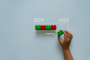 Loading new year 2024 to 2025 with child hand putting plastic block in progress bar. 