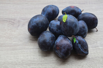 High angle, top view of pile violet purple dark blue plums on wooden table surface background. empty copy space for inscription.